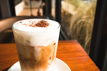 Close up Glass of iced coffee with chocolate powder and milk foam
