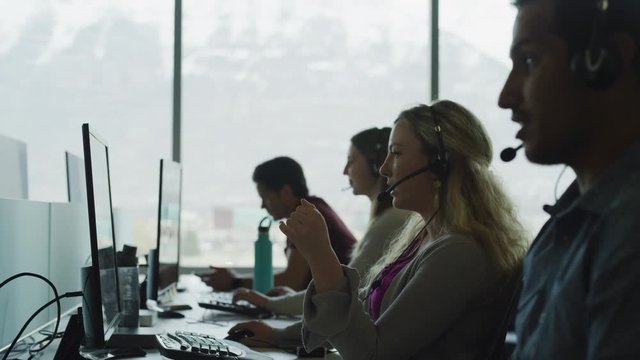 Panning shot of customer service representatives talking on telephones in call center / Pleasant Grove, Utah, United States