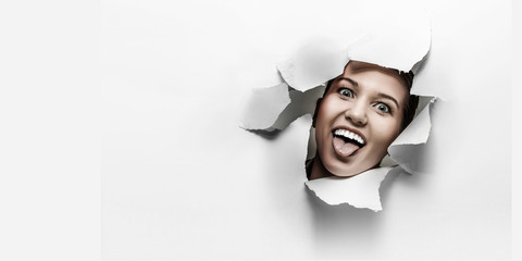 Woman looking out from a hole of torn paper