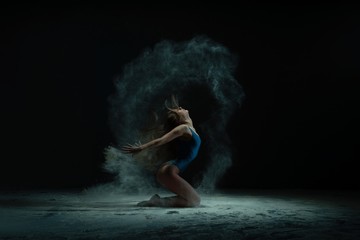 Fototapeta na wymiar Graceful barefoot woman dancing in cloud of dust