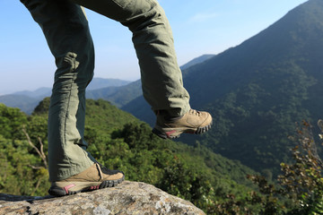 Fearless woman hiker walking to the cliff edge on mountain top