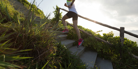 Determined woman running up on seaside mountain stairs