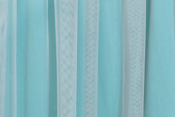 Light turquoise and grey background from a textile tulle material. Fabric with natural texture. Cloth backdrop.