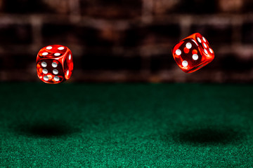 A very close up shot of 2 dice rolling on a green felt table top in very crisp focus, showing 2,4,5 and 6 on the faces.  The background is a very soft focused wall.
