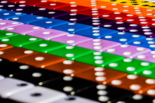 A Macro image of Diagonal rows of multicolored dice, lined in OCD fashion using the numbers to form perpendicular symmetry.  Foreground offers a softly focused field while rest is crisply focused
