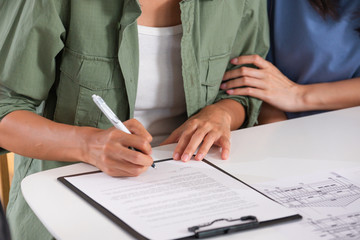 Happy asian lesbian couple sign contract for buy new house with realtor agent at new home after...