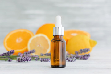 Bottle with citrus natural orange, lemon and lavender essential oil on wooden background.
