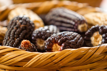 a handmade mexican basket with different variety of corns, blue corn