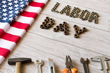 Labor day. American flag and Inscription labor day and various tools on a light wooden background.