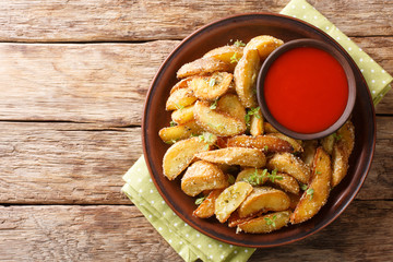 Fried potato wedges with parmesan and herbs with pepper sauce close-up on a plate. horizontal top...