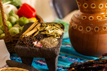 garlic, cinnamon, pepper and other mexican ingredients of mexican cuisine on a mexican metate, clay, mealing stone