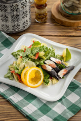 Fresh green salad with salmon cream cheese sushi on the side on wooden table
