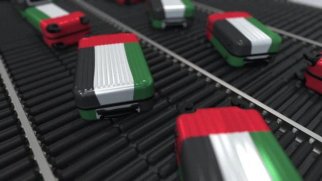 Many travel suitcases featuring flag of the United Arab Emirates on roller conveyer. UAE tourism conceptual animation