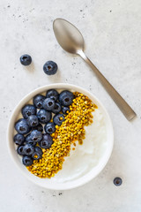 Bowl of greek yogurt, bee pollen and fresh berries on white stone background