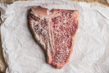 Raw fresh marble T-bone meat on the rustic background. Selective focus. Shallow depth of field.