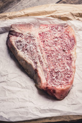 Raw fresh marble T-bone meat on the rustic background. Selective focus. Shallow depth of field.