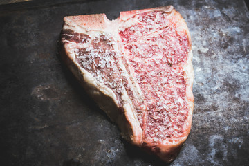 Raw fresh marble T-bone meat on the rustic background. Selective focus. Shallow depth of field.
