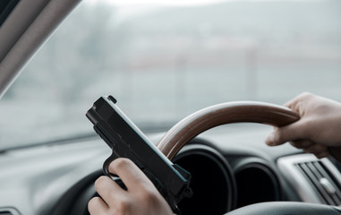 man driving  car hand gun