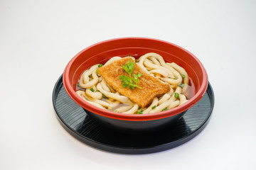 Bowl of Japanese udon noodles with grilled chopped fish isolated on white background