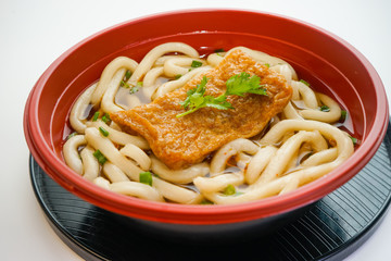 Bowl of Japanese udon noodles with grilled chopped fish isolated on white background