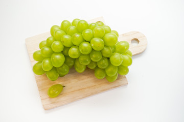 Green grapes on chopping board isolated on white background