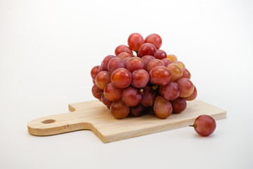 Red grapes on chopping board isolated on white background