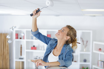 portrait of young woman roller painting the ceiling