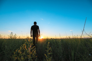 man in field at sunset