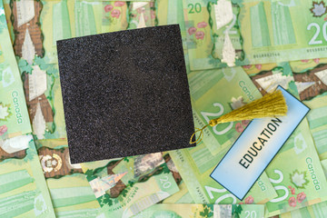 Fototapeta na wymiar University Mortarboard academic cap on Canadian Dollar notes