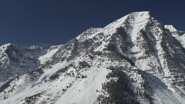 Aerial panning shot of snow covered mountain range / Aspen Grove, Utah, United States