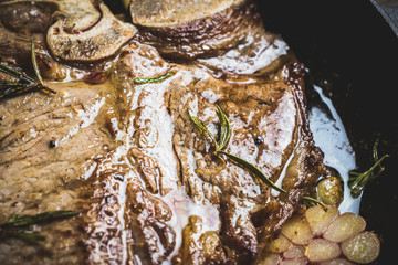 Grilled T-bone steak on the frying pan with garlic and rosemary. Selective focus. Shallow depth of field.