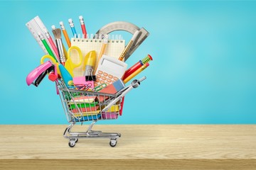Stationery objects in mini supermarket cart on wooden desk