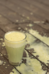 Ice cold sweet green lime tea drink on the wooden table with outdoor sun lighting with ice cubes and splashes of drink