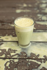 Ice cold sweet green lime tea drink on the wooden table with outdoor sun lighting with ice cubes and splashes of drink