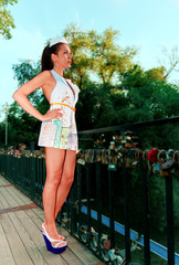 Sexy girl stands on the bridge in full-length in a fashionable paper dress looking straight