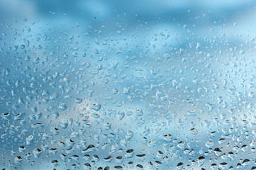 viele kleine Wassertropfen auf einer Scheibe in blau bei Regen