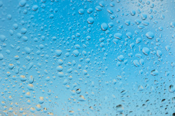 viele kleine Wassertropfen auf einer Scheibe in blau bei Regen