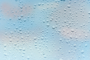 viele kleine Wassertropfen auf einer Scheibe in blau bei Regen