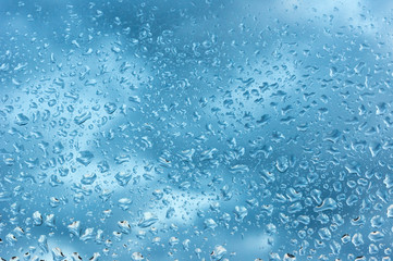 viele kleine Wassertropfen auf einer Scheibe in blau bei Regen