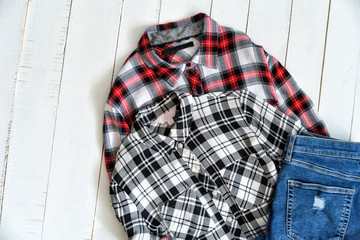 Clothes concept. Two checkered shirts and jeans on a wooden background. Top view