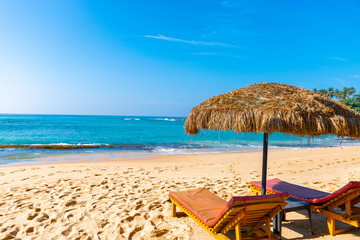 Two wooden sun beds on the sand beach of Unawatuna, Sri Lanka.