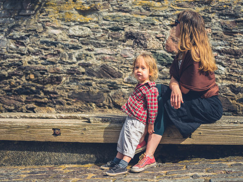 Young mother and toddler relaxing by stone wall