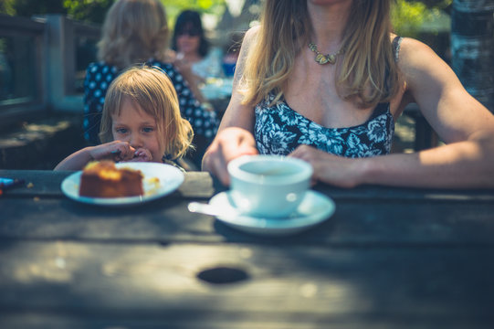 Young mother and toddler having coffee and cake