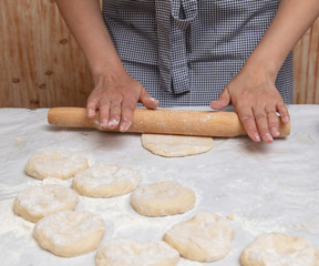 Girl rolls the dough in the kitchen