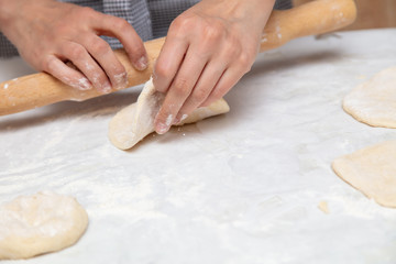 Girl rolls the dough in the kitchen