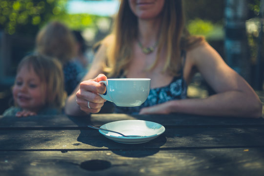 Young mother with toddler drinking coffee in cafe outdoors
