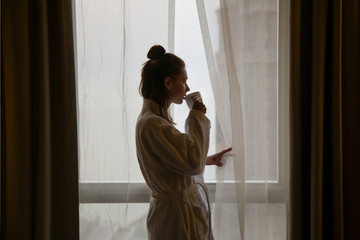 Woman drinking the first-morning coffee next to the window
