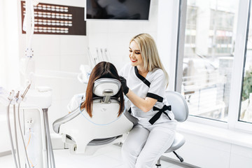 Pretty young female dentist making examination and treatment for young female patient in dental clinic.