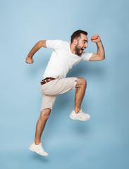 Full length photo of happy caucasian man in casual white t-shirt rejoicing and smiling while running
