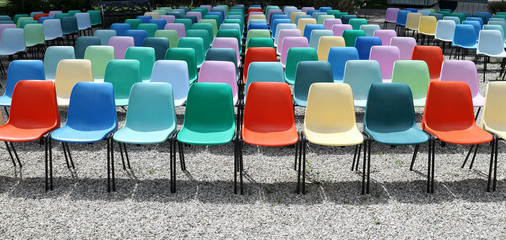 Long rows of empty colorful  plastic chairs geometrically arranged under the sun. Texture and...